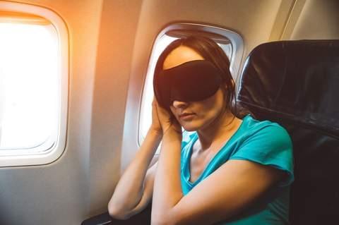 woman flying in an airplane with a sleep mask on