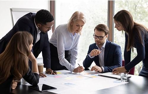 board meeting with people looking at charts on a table